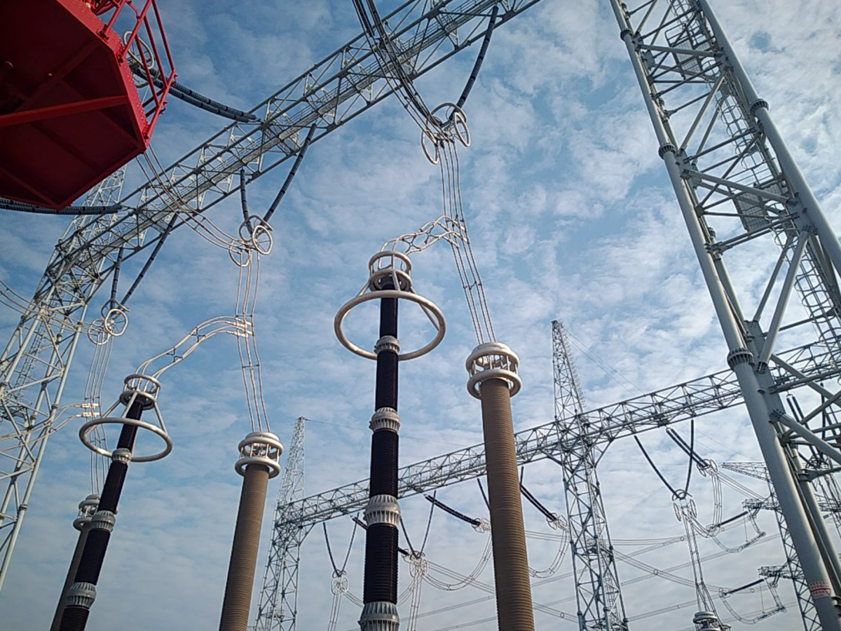 High-voltage terminal and conductor assemblies viewed from below in an outdoor electrical substation.