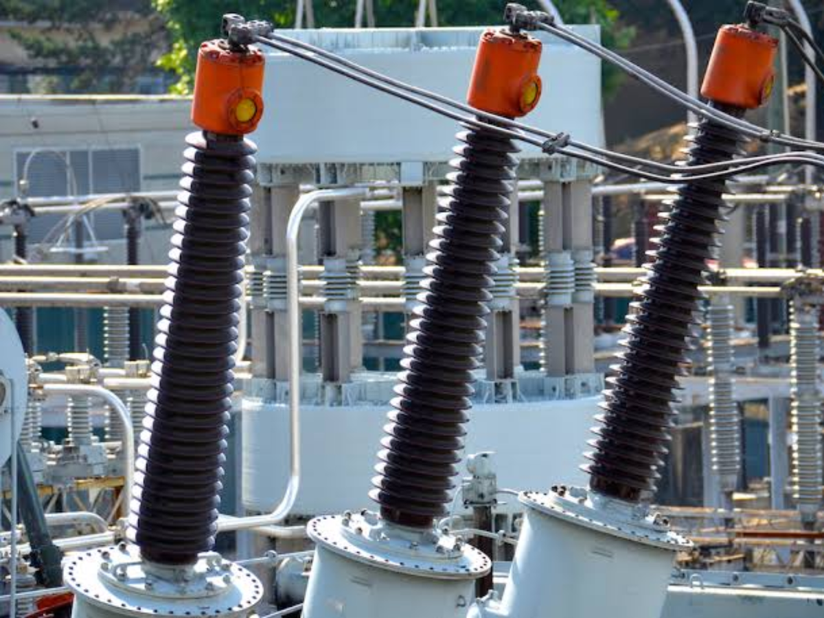 Visible image: Three high-voltage bushing and terminal assemblies in an outdoor electrical substation.